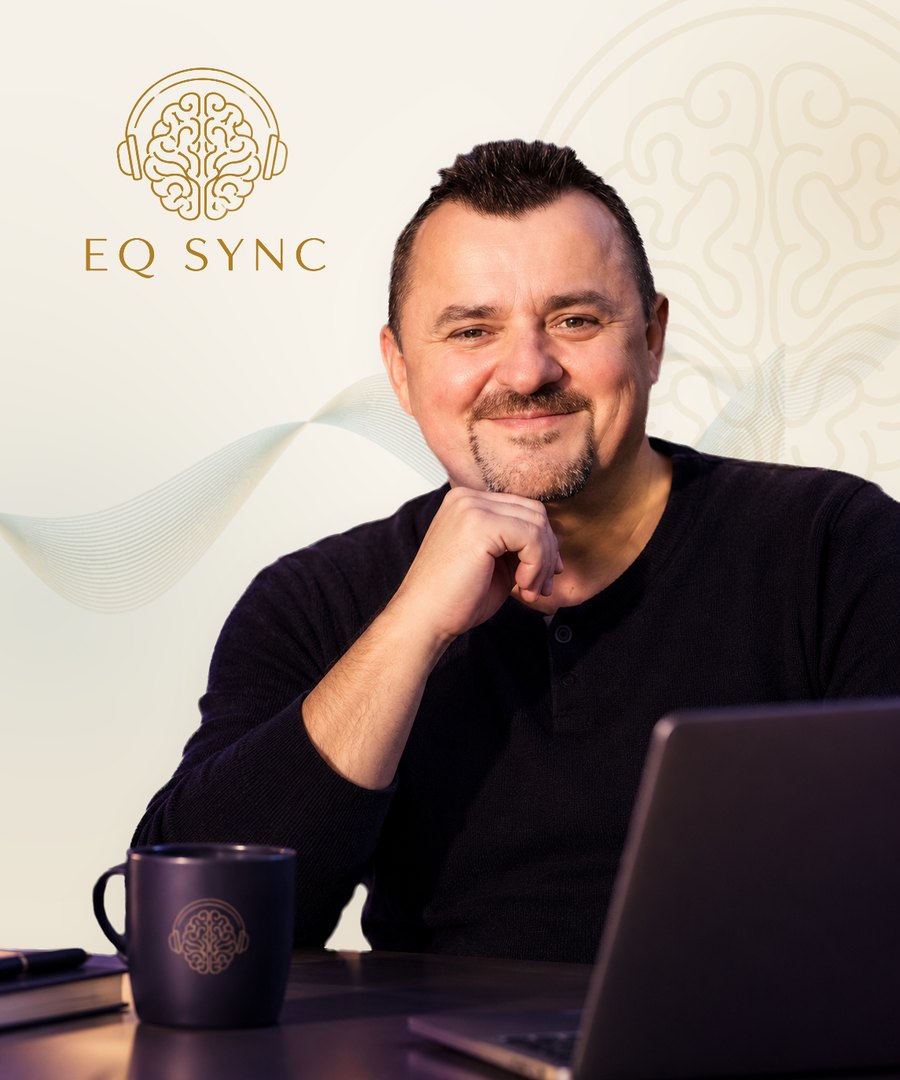 Adrian Turcu, neuroterapeut și fondator EQ-SYNC, zâmbind la birou, lângă laptop
